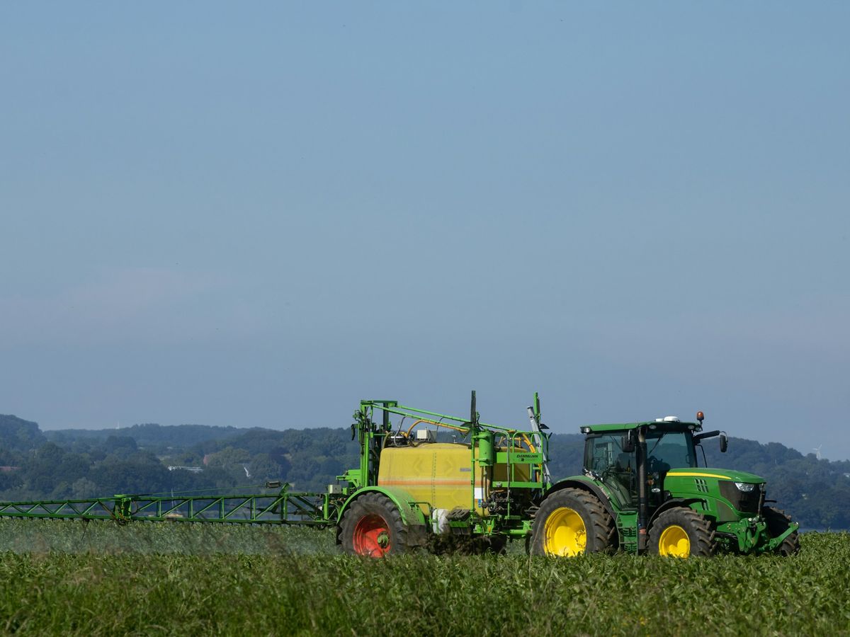 Traktor mit Anbau-Feldspritze bei der Pflanzenschutzmaßnahme