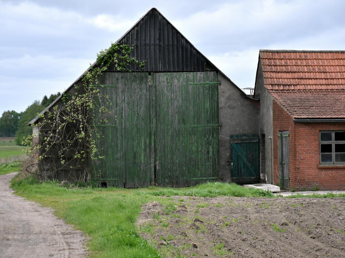 Alte Holzscheune und Backsteingebäude auf einem Hof